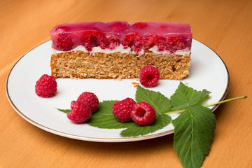 Ein Stück Himbeerkuchen auf einem Porzellanteller, Holztisch
