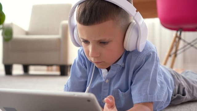 Boy in headphones using digital tablet on floor
