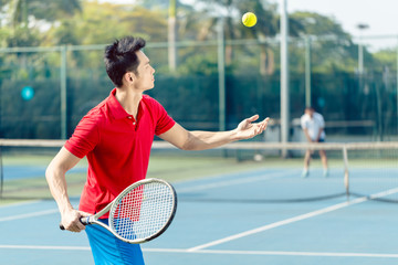 Chinese professional tennis player ready to hit the ball with the racket after tossing while...