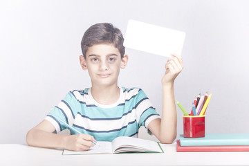Cute school boy holding a blank advertising banner with copy space
