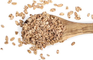 Organic barley flakes pile with wooden spoon, isolated on white background