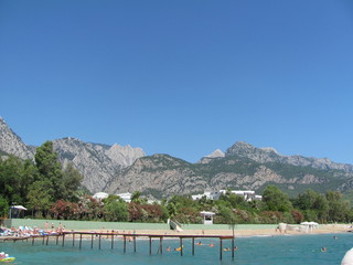 Fototapeta premium View of the beach and an empty pier from the sea, mountain ranges in the distance, beauty and peace