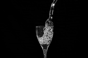 water falling in a transparent wine glass creating splash and bubbles