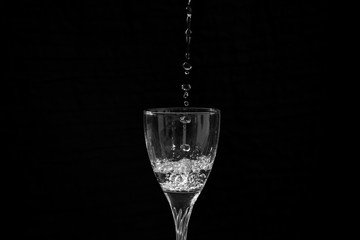 water falling in a transparent wine glass creating splash and bubbles