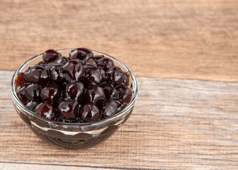 Tapioca Pearl , Bubble topping for tea or other beverage, in a cup, place on wooden table. Copy space