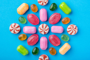 Many multicolored delicious candies on a blue background