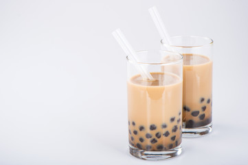 A glass of sweet milk bubble tea with tapioca pearls, and straw on white background. Copy space