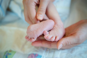 Woman's hand holding the legs of a newborn baby