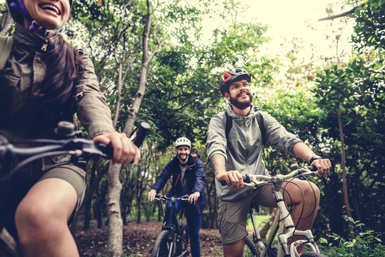 Group Of Friends Ride Mountain Bike In The Forest Together