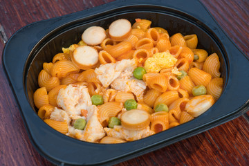 lunch box set of stir fried Macaroni with ketchup on wood table