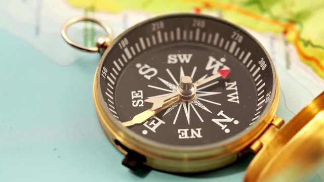 concept of travel, adventure, expedition, business, choice and possibilities - a golden compass lying on an abstract map with a red arrow that shows the direction