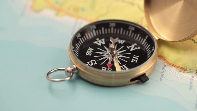 concept of travel, adventure, expedition, business, choice and possibilities - a golden compass lying on an abstract map with a red arrow that shows the direction