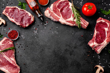Meat raw steaks lie on a black background with vegetables, tomatoes, marasmade, mushrooms. background image. side view, copy space, top view