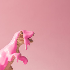 Pink paint dripping on dinosaur toy. Creative minimal concept.