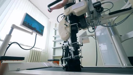 Medical room with a male patient undergoing a walking track training. Modern medical recovery device.