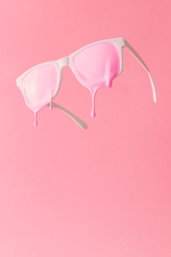 Pink paint dripping out of white painted sunglasses. Creative fashion minimal concept.