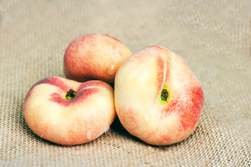 Three peaches lying on burlap