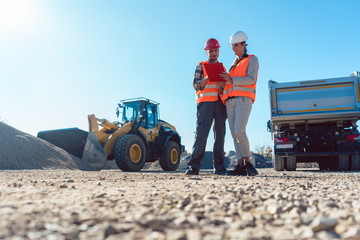Worker and engineer on earthworks construction site planning, woman and man