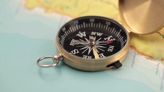 concept of travel, adventure, expedition, business, choice and possibilities - a golden compass lying on an abstract map with a red arrow that shows the direction