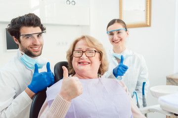 Dentists and patient in surgery being excited showing thumbs up 