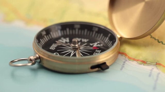 concept of travel, adventure, expedition, business, choice and possibilities - a golden compass lying on an abstract map with a red arrow that shows the direction