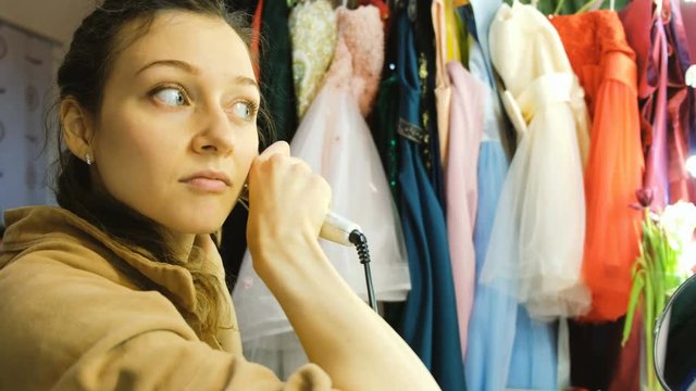 Young beautiful girl curls her hair on a curling robe in the dressing room