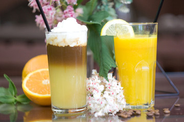 Glasses with fresh orange juice and coffee cocktail on table.