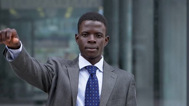 Young African businessman thumbs down. Refused, bankruptcy- slow motion