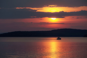 Sunset with red sky, boat crossing the scene