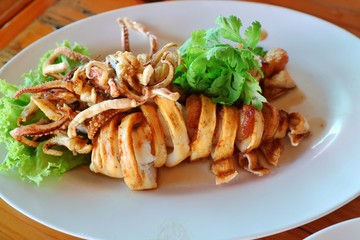Crisp fried calamari with coriander on white plate. Thai seafood. Food concept.