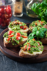 Bruschetta with fresh pesto, mozzarella and cherry tomatoes on cutting board