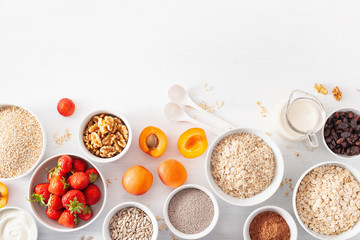 Fototapeta na wymiar variaty of raw cereals, fruits and nuts for breakfast. Oatmeal flakes and steel cut, barley, walnut, chia, apricot, strawberry. Healthy ingredients