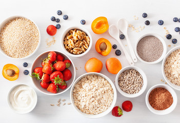 variaty of raw cereals, fruits and nuts for breakfast. Oatmeal flakes and steel cut, barley, walnut, chia, apricot, strawberry. Healthy ingredients