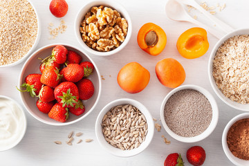variaty of raw cereals, fruits and nuts for breakfast. Oatmeal flakes and steel cut, barley, walnut, chia, apricot, strawberry. Healthy ingredients
