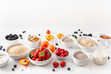 variaty of raw cereals, fruits and nuts for breakfast. Oatmeal flakes and steel cut, barley, walnut, chia, apricot, strawberry. Healthy ingredients