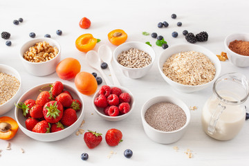 variaty of raw cereals, fruits and nuts for breakfast. Oatmeal flakes and steel cut, barley, walnut, chia, apricot, strawberry. Healthy ingredients