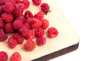 Forest raspberry on a wooden board, on a white background.