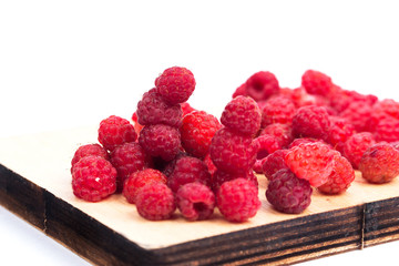 Forest raspberry on a wooden board, on a white background.