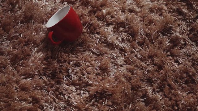 Fallen cup. Empty cup of coffee in red color   falling down on carpet flipping and bouncing in slow motion hd video.