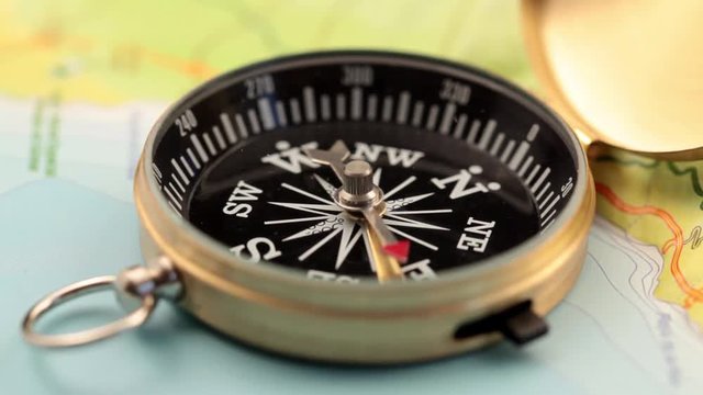 concept of travel, adventure, expedition, business, choice and possibilities - a golden compass lying on an abstract map with a red arrow that shows the direction