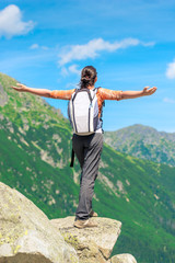 Obraz premium a happy tourist is standing by the cliff at the edge of the rock with arms stretched out to the side