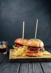 homemade juicy burgers on wooden board. Street food, fast food. with French fries and glass of  cola