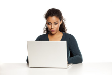 Smiling and positive young african-american woman with beautiful face using laptop computer, working project at desk on white background