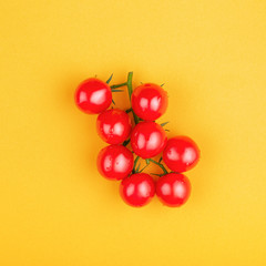 Bunch of fresh cherry tomatoes on yellow background. Top view, minimal styled composition.