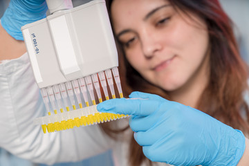 Woman technician with multipipette in genetic laboratory PCR research. Student girl use pipette