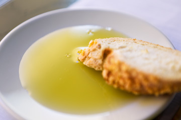 One slice of bread and olive oil in a white plate.