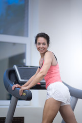 Naklejka na ściany i meble attractive sport woman on running track. Girl with a smile on treadmill