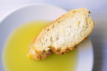 One slice of bread and olive oil in a white plate.