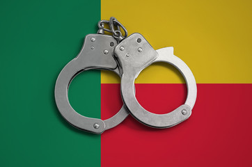 Benin flag  and police handcuffs. The concept of observance of the law in the country and...