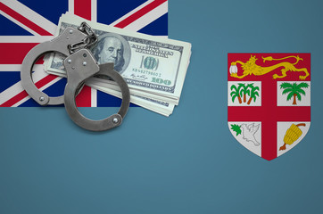 Fiji flag  with handcuffs and a bundle of dollars. The concept of breaking the law and thieves...